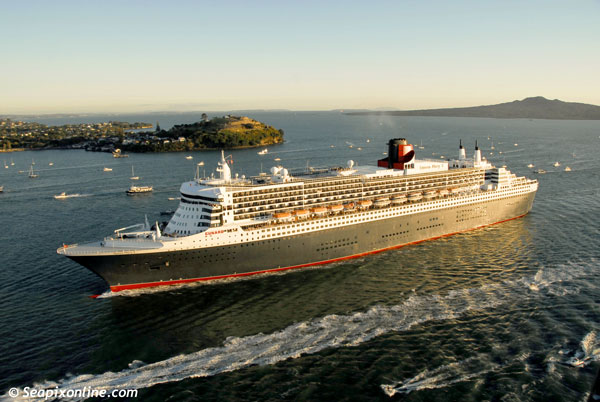 QUEEN MARY 2 (2003/148528grt/IMO 9241061) sails majestically into Aucklands' Waitemata Harbour just after sunrise accompanied by a flotilla of hundreds of yachts, private and commercial launches as helicopters and aircraft circle overhead. She arrived in port for a one-day stop-over during the San Francisco-Sydney leg of her 80-night maiden world cruise. She departed later that night to meet up with QUEEN ELIZABETH 2 in Sydney Harbour, Australia. 17 February 2007. Photo by SeapixOnline.com/Trevor Coppock